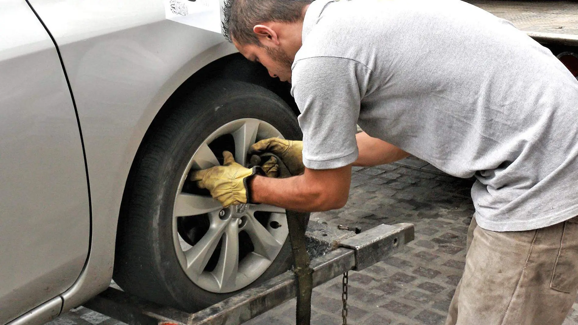 persona revisa llanta de auto en grua 